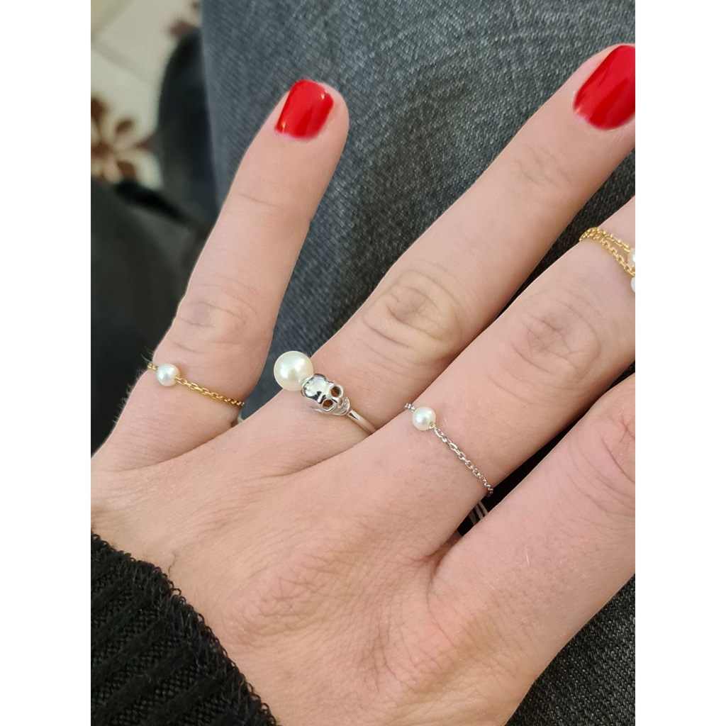 Bague Claverin en or blanc 18 carats avec perle blanche et motif tête de mort portée sur un doigt