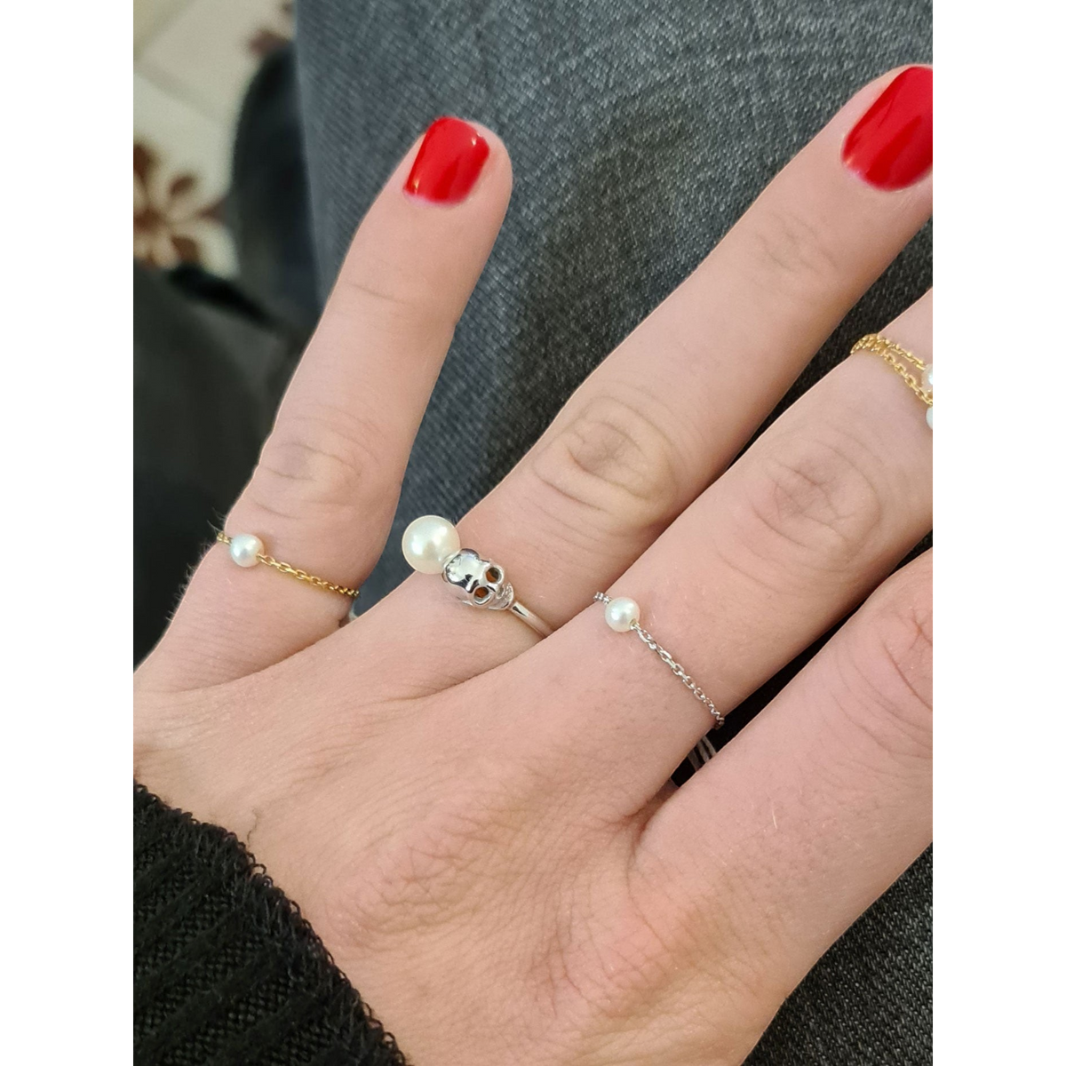 Bague Claverin en or blanc 18 carats avec perle blanche et motif tête de mort portée sur un doigt