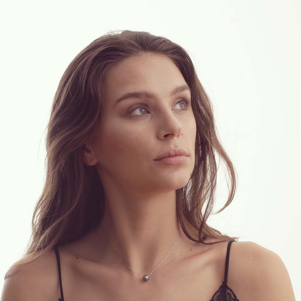 Femme portant un pendentif Claverin avec une perle noire de Tahiti sur une fine chaîne en or blanc 18 carats